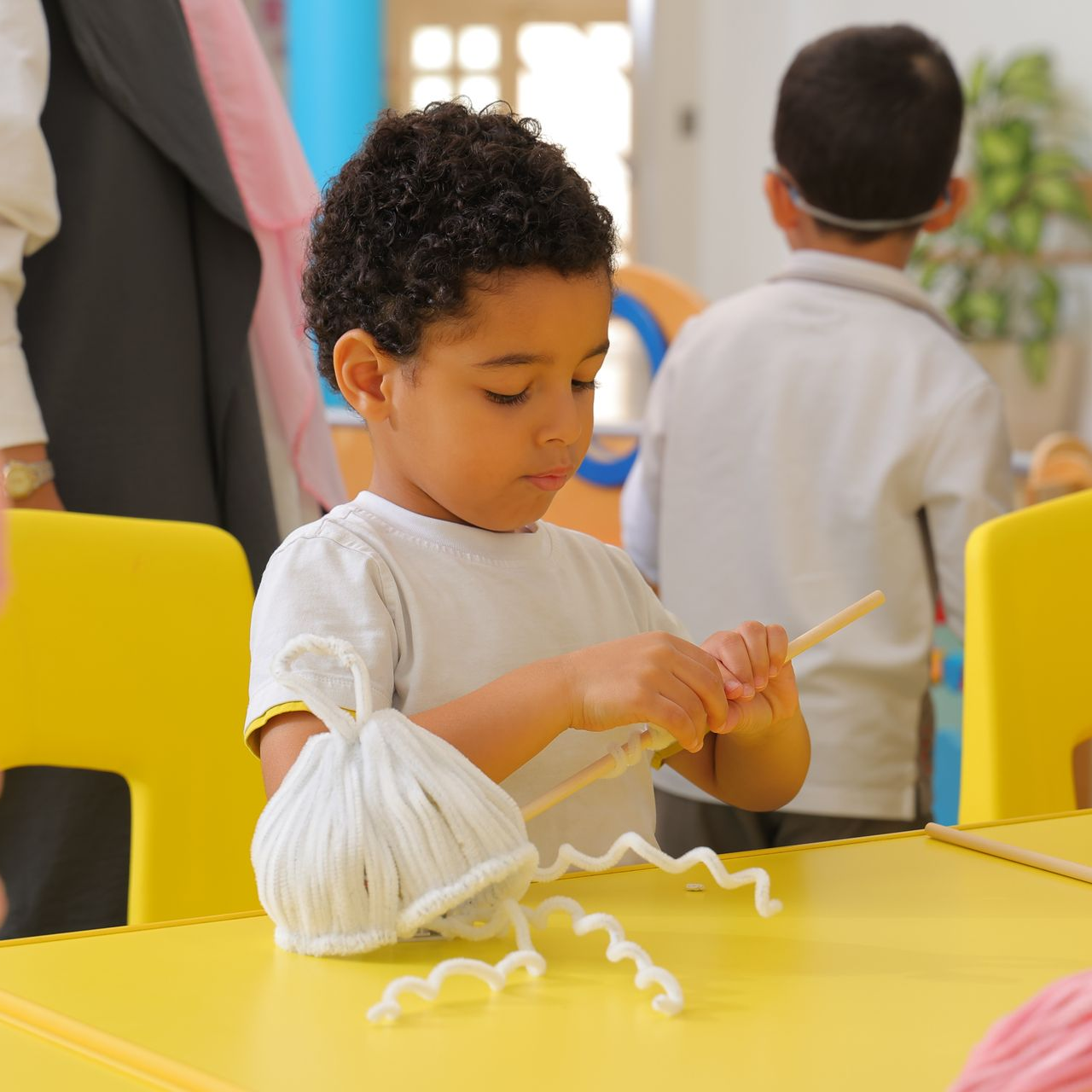 A group of children are sitting at a table with papers and pencils