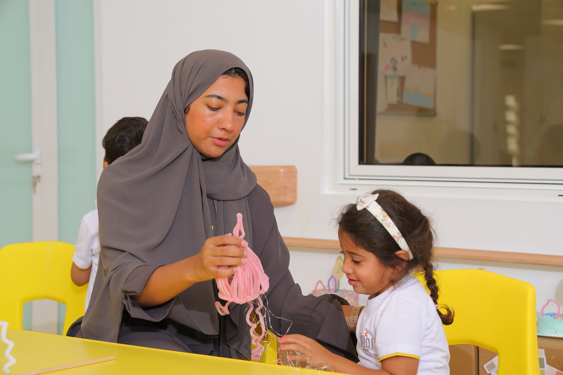 Teacher reading to children seated around colorful tables in a bright classroom