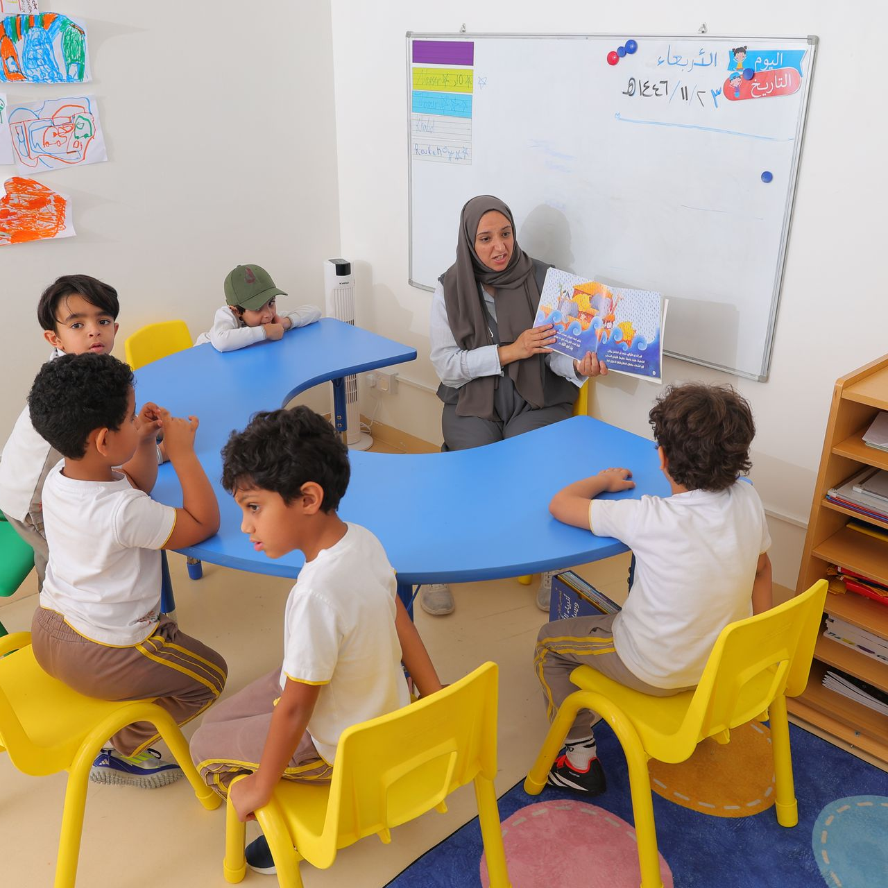 A group of young boys are sitting at a table drawing on papers