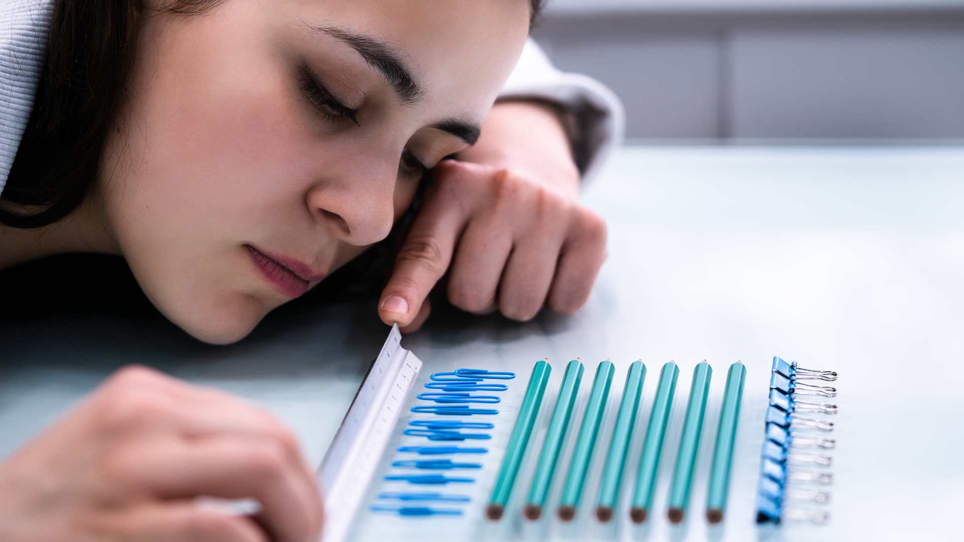woman lining up the ruler, paper clips and pencils on the table