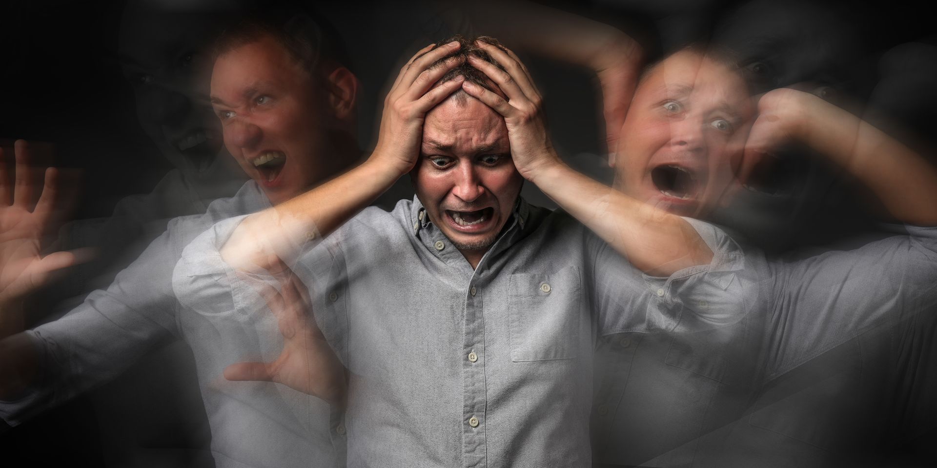 A distressed man holds his head as blurred duplicates surround him, expressing panic and anxiety now