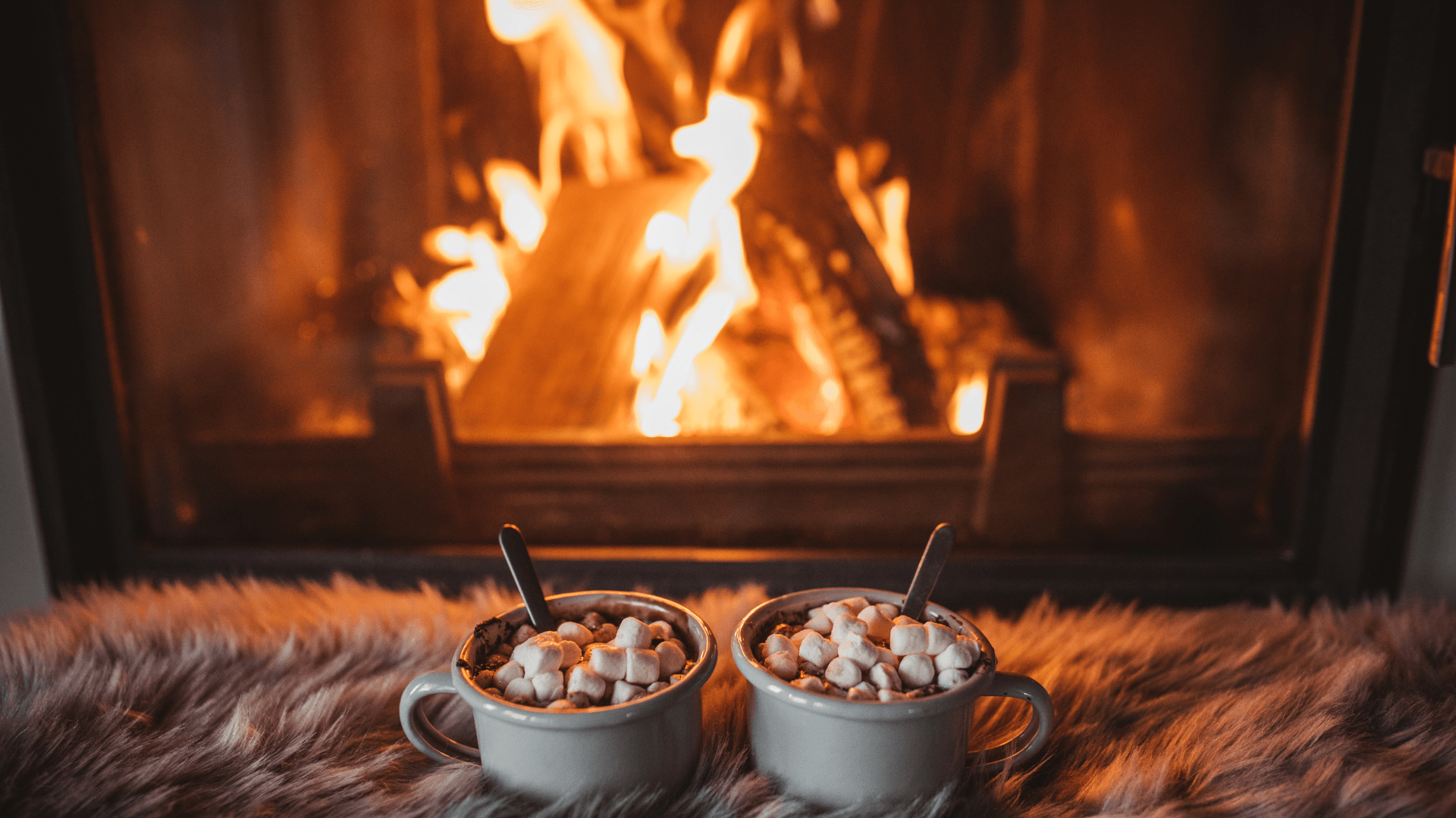 two hot coco placed in front of a cozy fire place