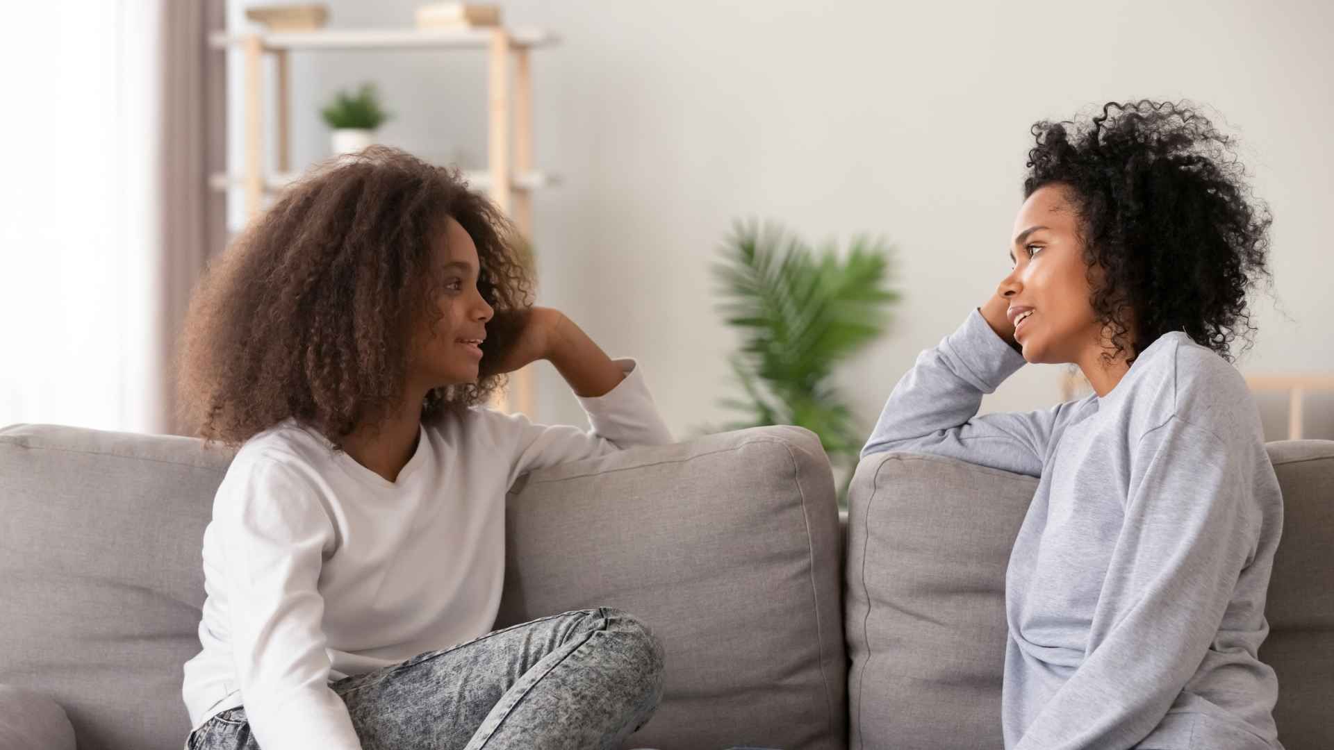 two female talking on a sofa