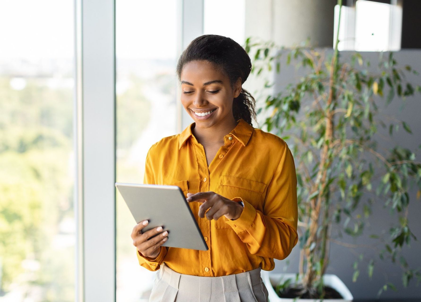 A woman in a yellow shirt is using a tablet computer.