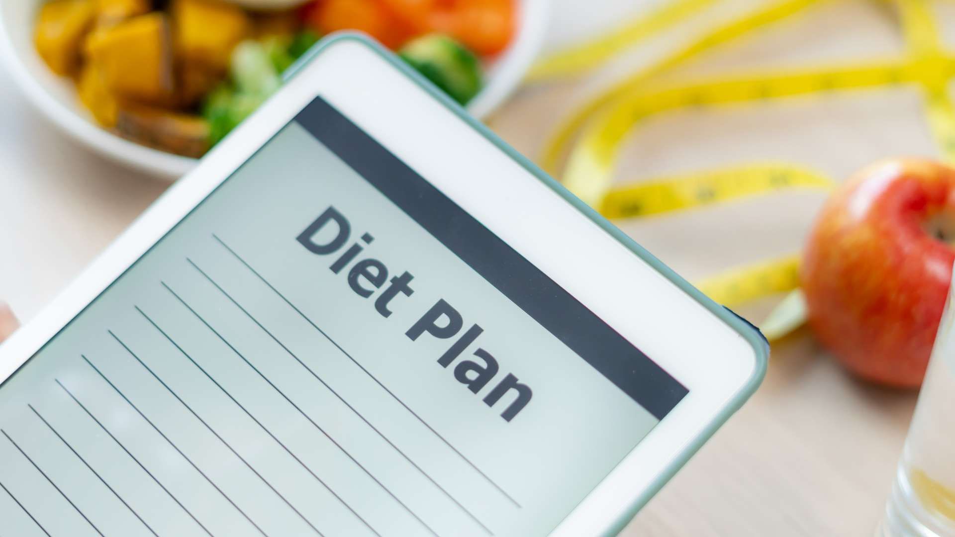 Tablet screen showing a “Diet Plan” document on a table with fruit in the background