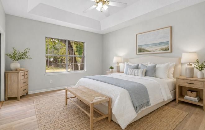Bright bedroom with a bed, bench, nightstands, window, and light wood flooring