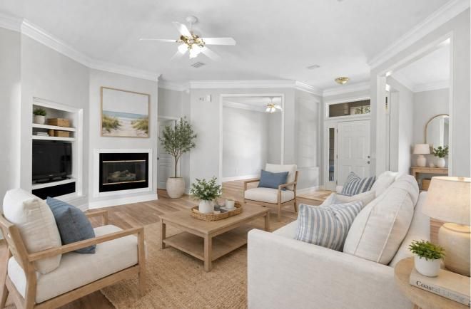 Bright living room with white sofas, fireplace, wood coffee table, and neutral decor