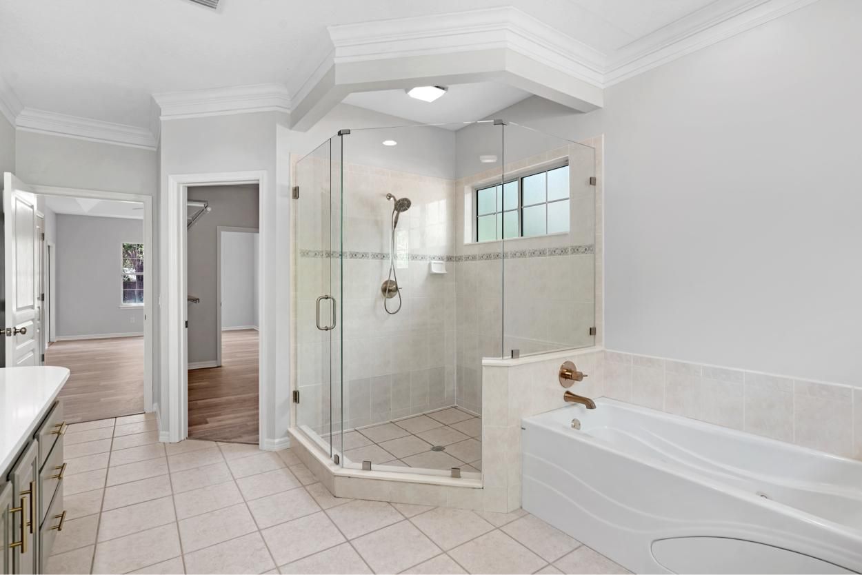 Bright white bathroom with glass shower, soaking tub, and tiled floor