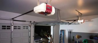 Garage interior with a red ceiling-mounted garage door opener above an open garage door