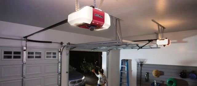 Garage interior with open door, red garage door opener, and a car partially visible inside
