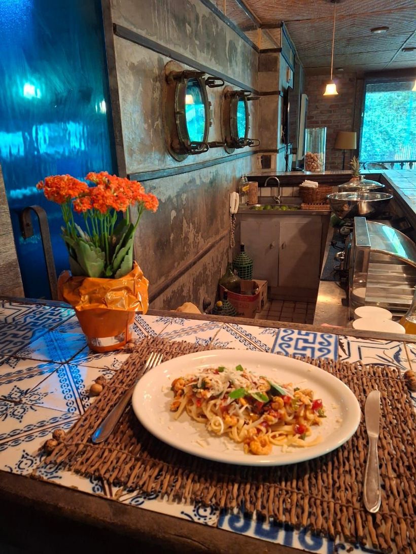 Um prato de comida está sobre uma mesa ao lado de um vaso de flores.-Pousada-Pilar
