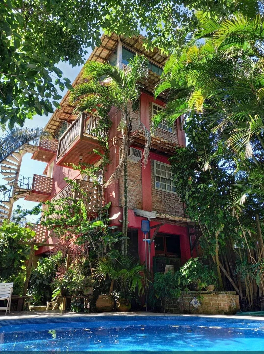 Uma casa grande com uma piscina na frente, cercada por árvores.-Pousada-Pilar