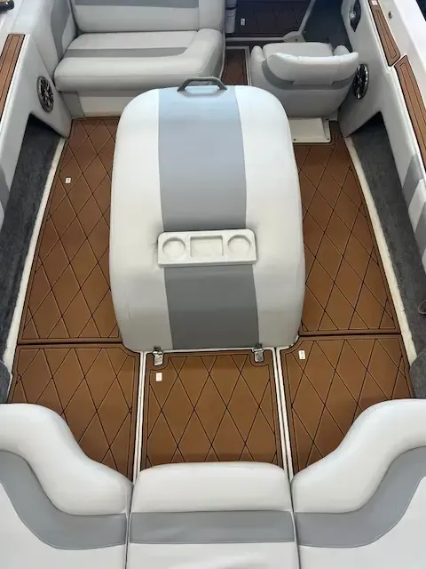 Boat interior with gray and white seats, brown diamond-patterned flooring, and a central seat with cupholders.