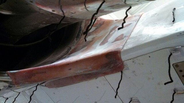 Close-up of a damaged, possibly interior, white structure with a curved, reddish section.