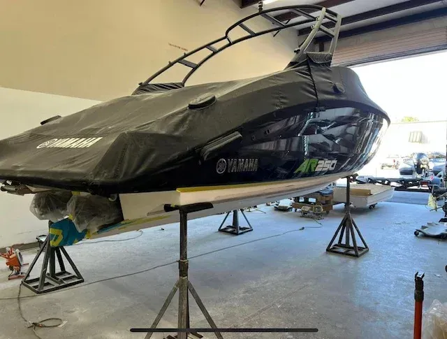 Yamaha jet ski on stands, covered with black tarp, inside a garage.