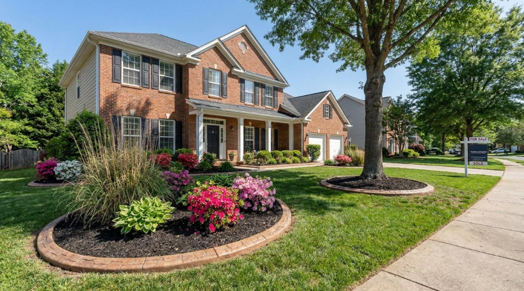Brick suburban house with manicured lawn, flower bed, and sidewalk on a sunny day