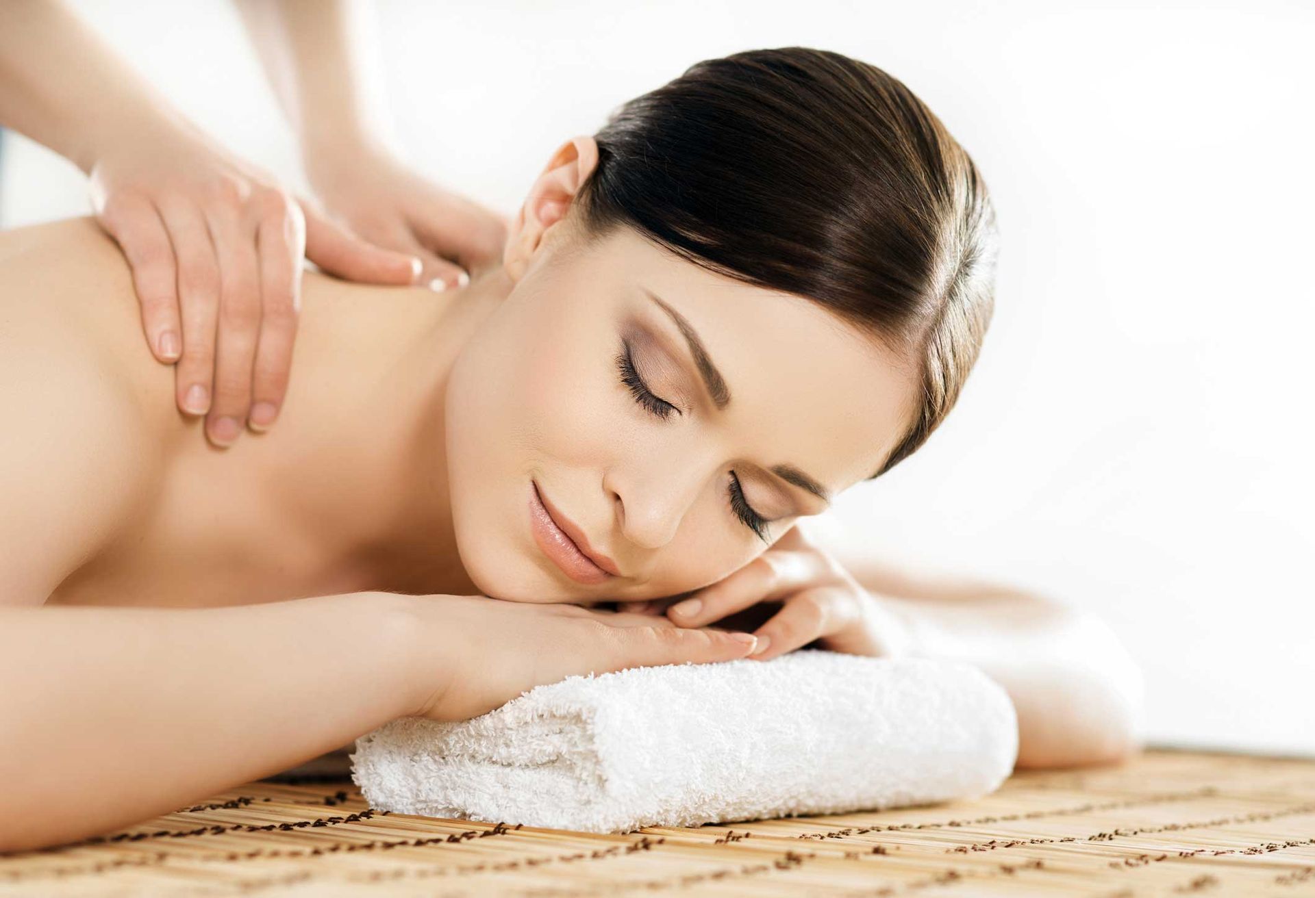 Woman receiving a massage with a towel under her head in a bright spa setting