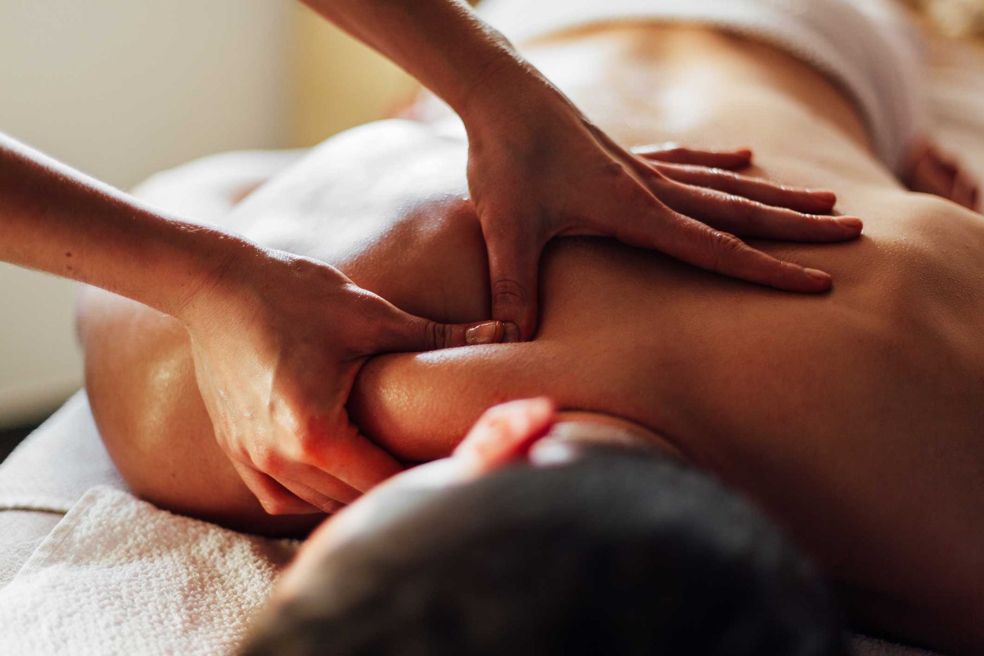 Hands giving a back massage on a person lying face down on a massage table