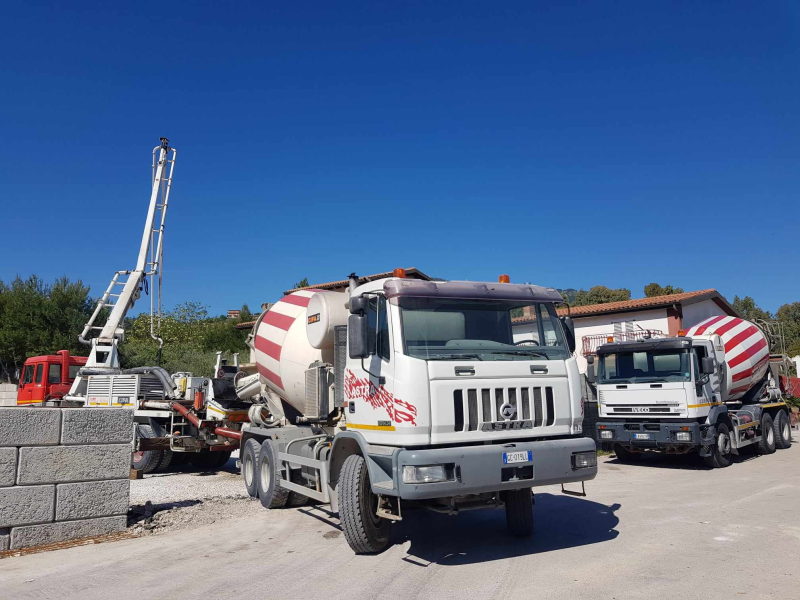 Due autobetoniere in un cantiere edile sotto un cielo azzurro e limpido.