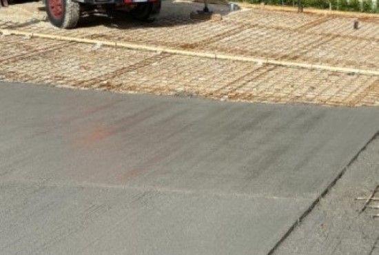 Una strada asfaltata che incontra un attraversamento in ciottoli color beige, con parte di un veicolo visibile in alto a sinistra.