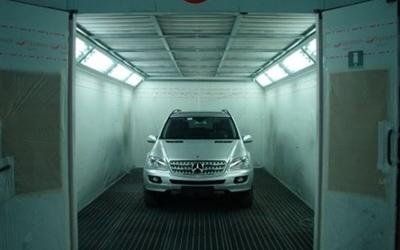 Un SUV bianco all'interno di un autolavaggio automatico con luci intense dall'alto.