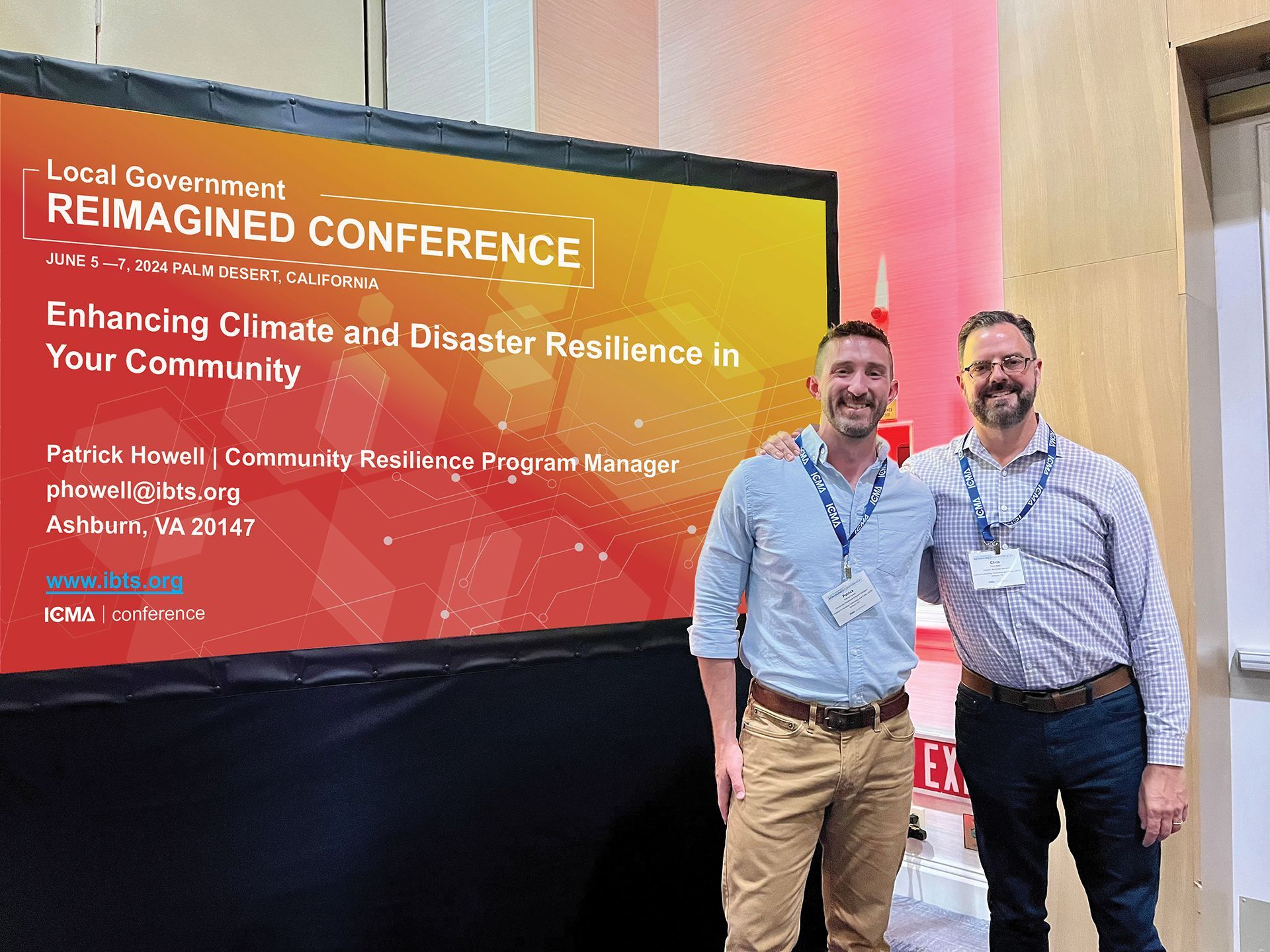 Two men standing in front of a large screen that says reimagined conference