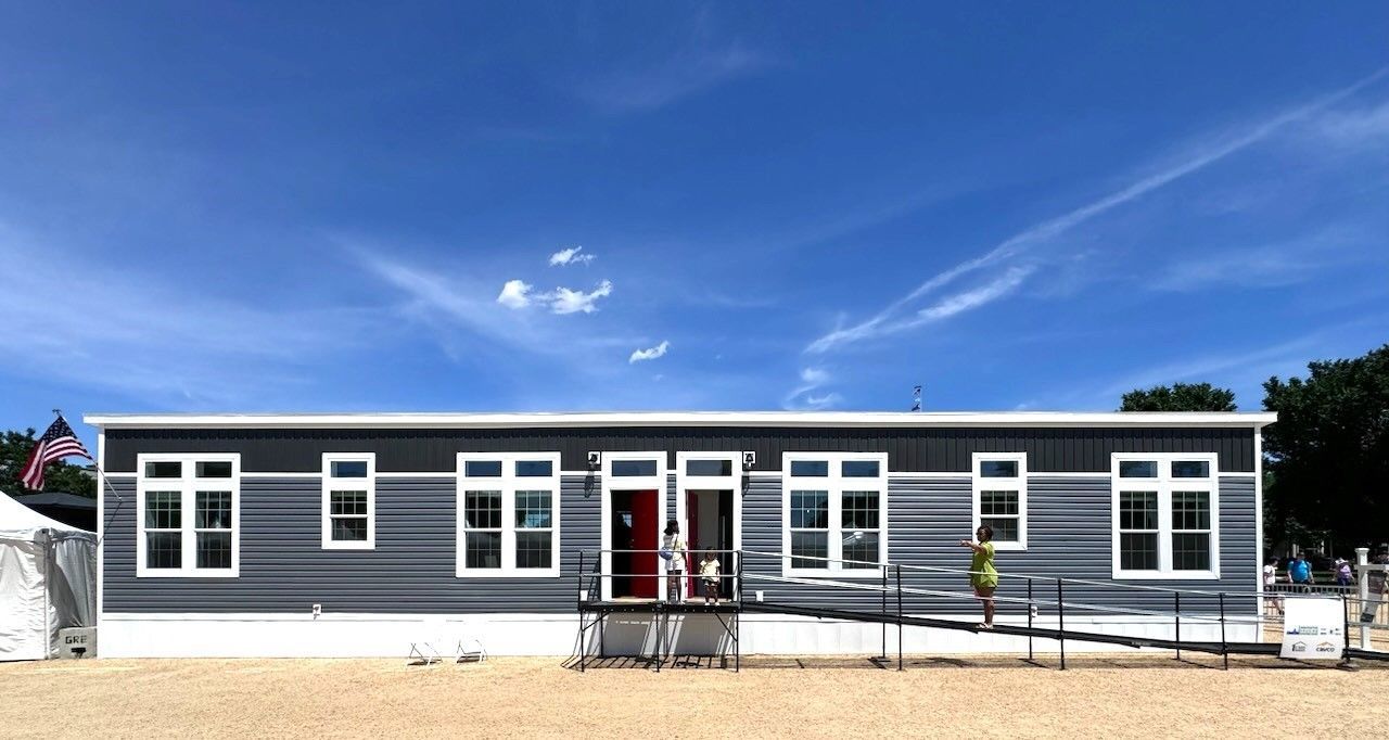 A mobile home with a handicap ramp is sitting on top of a dirt field.