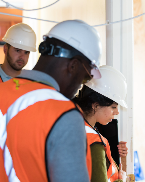 A group of construction workers wearing hard hats and orange vests