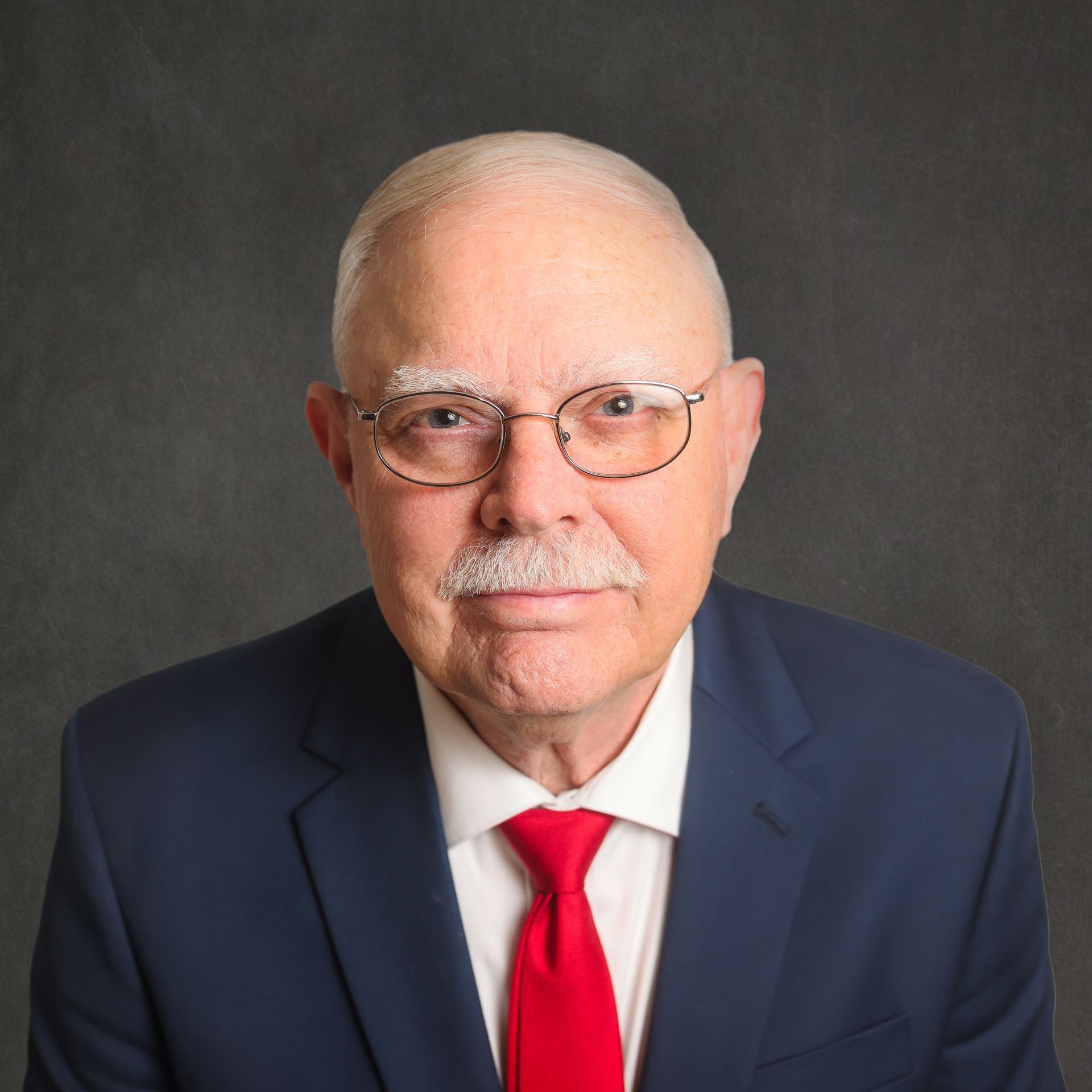 A man in a suit and tie with glasses and a mustache