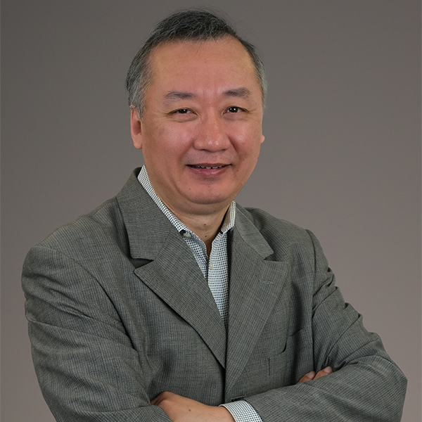 A man in a suit is smiling with his arms crossed
