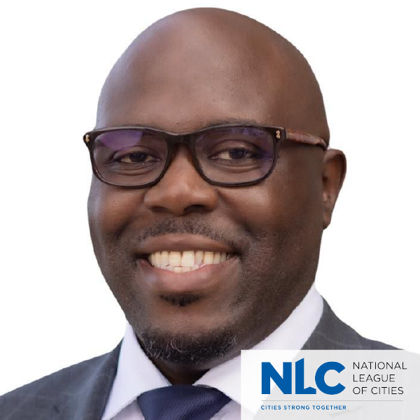A man wearing glasses and a suit is a member of the national league of cities