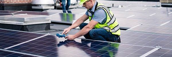 A man is installing solar panels on a roof.