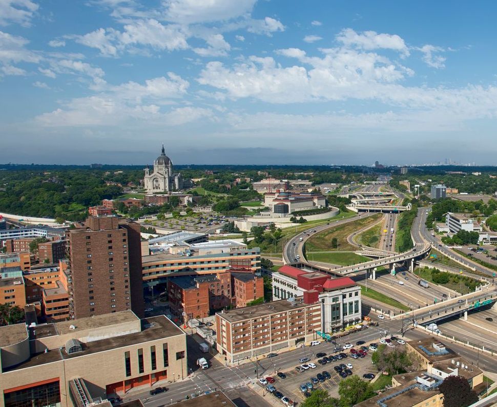 Vista aérea de St. Paul, Minnesota, con un paisaje urbano con edificios, carreteras y una importante catedral bajo un cielo azul con nubes.