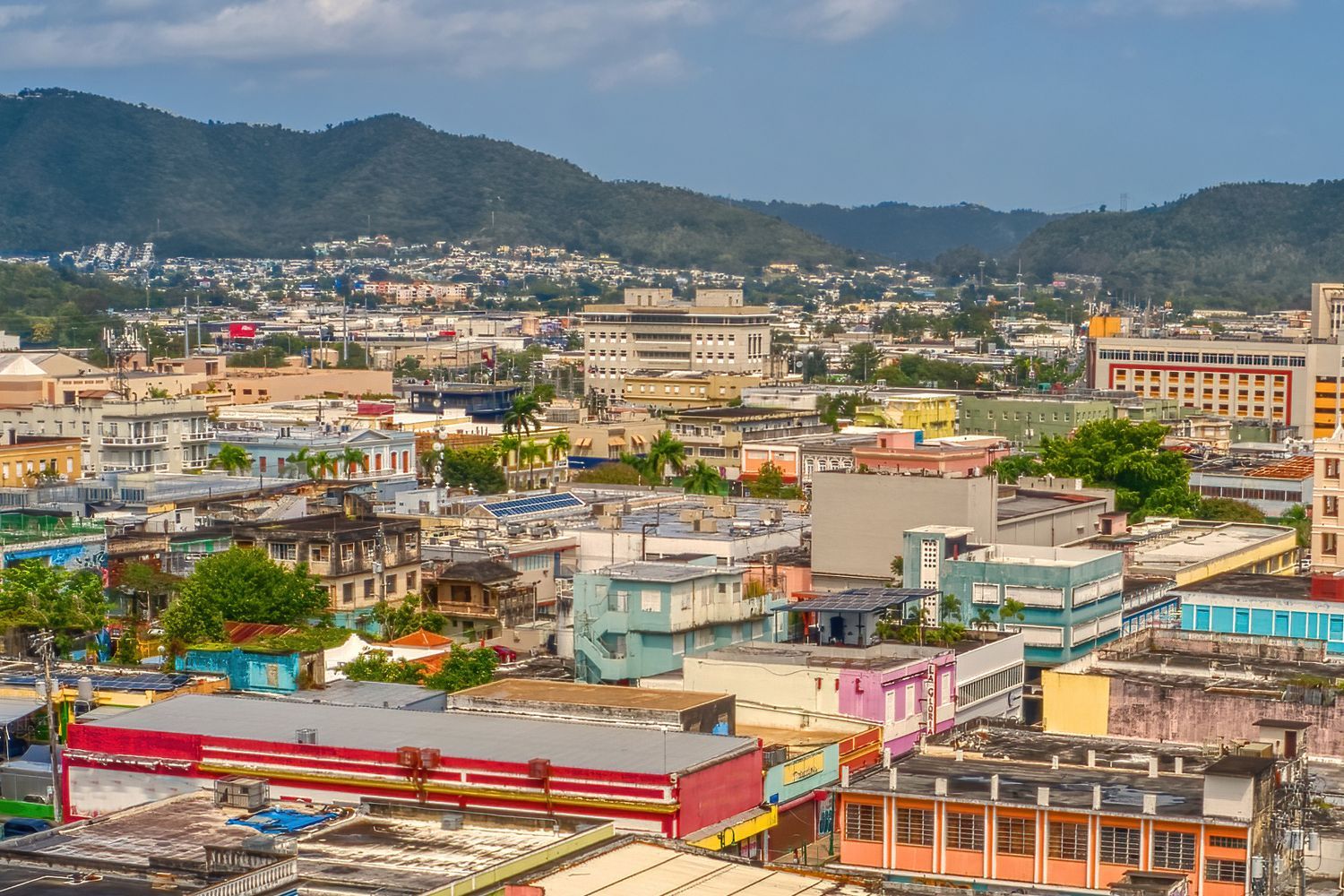 An aerial view of a city in puerto rico with mountains in the background.
