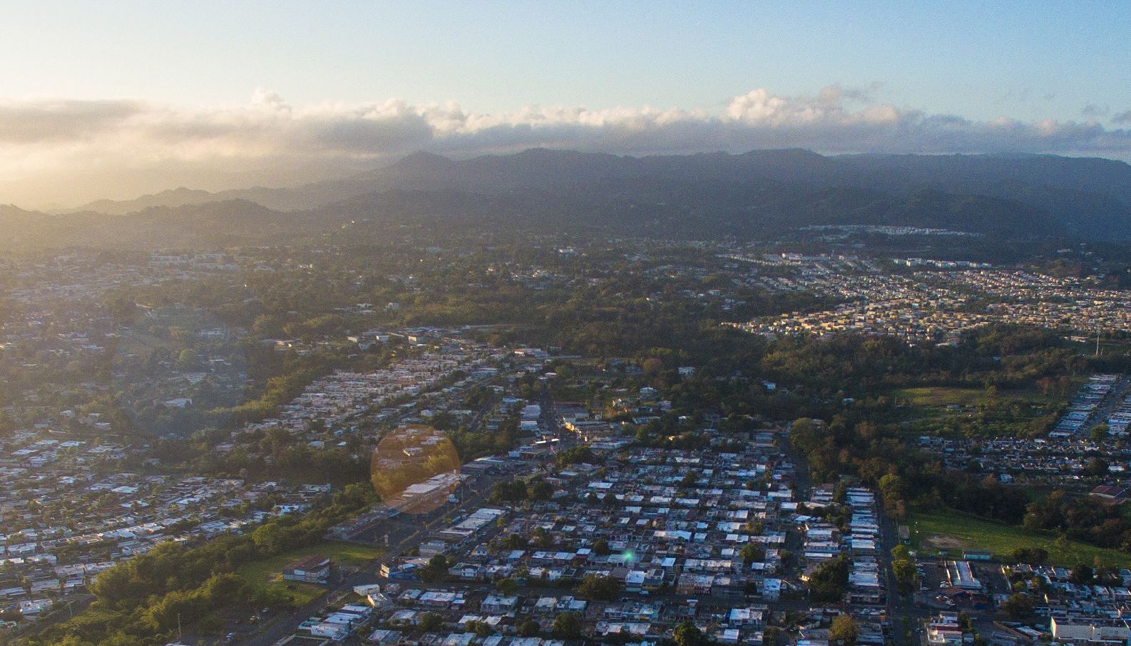 An aerial view of a city with mountains in the background at sunset.