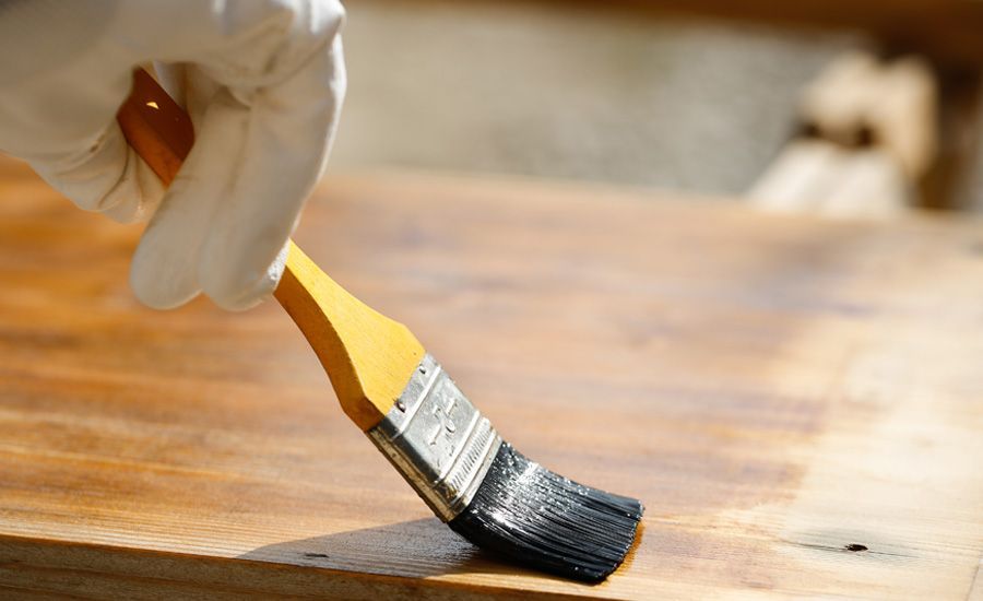 Una persona sta dipingendo un pezzo di legno con un pennello.