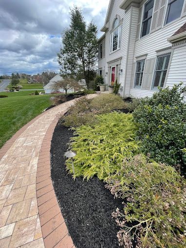 A brick walkway leading to a large white house.