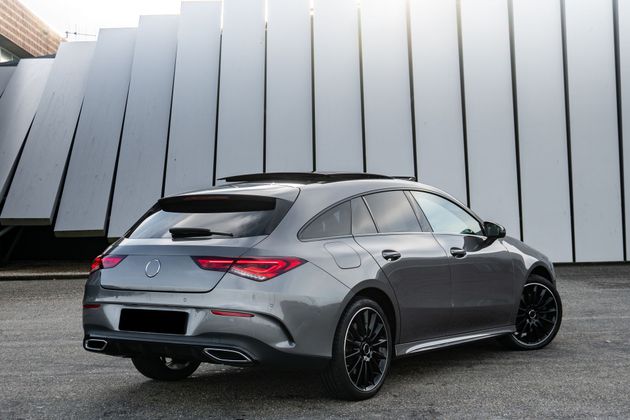 A grey Mercedes-Benz CLA Shooting Brake parked at an angle in front of a modern, vertically paneled building.