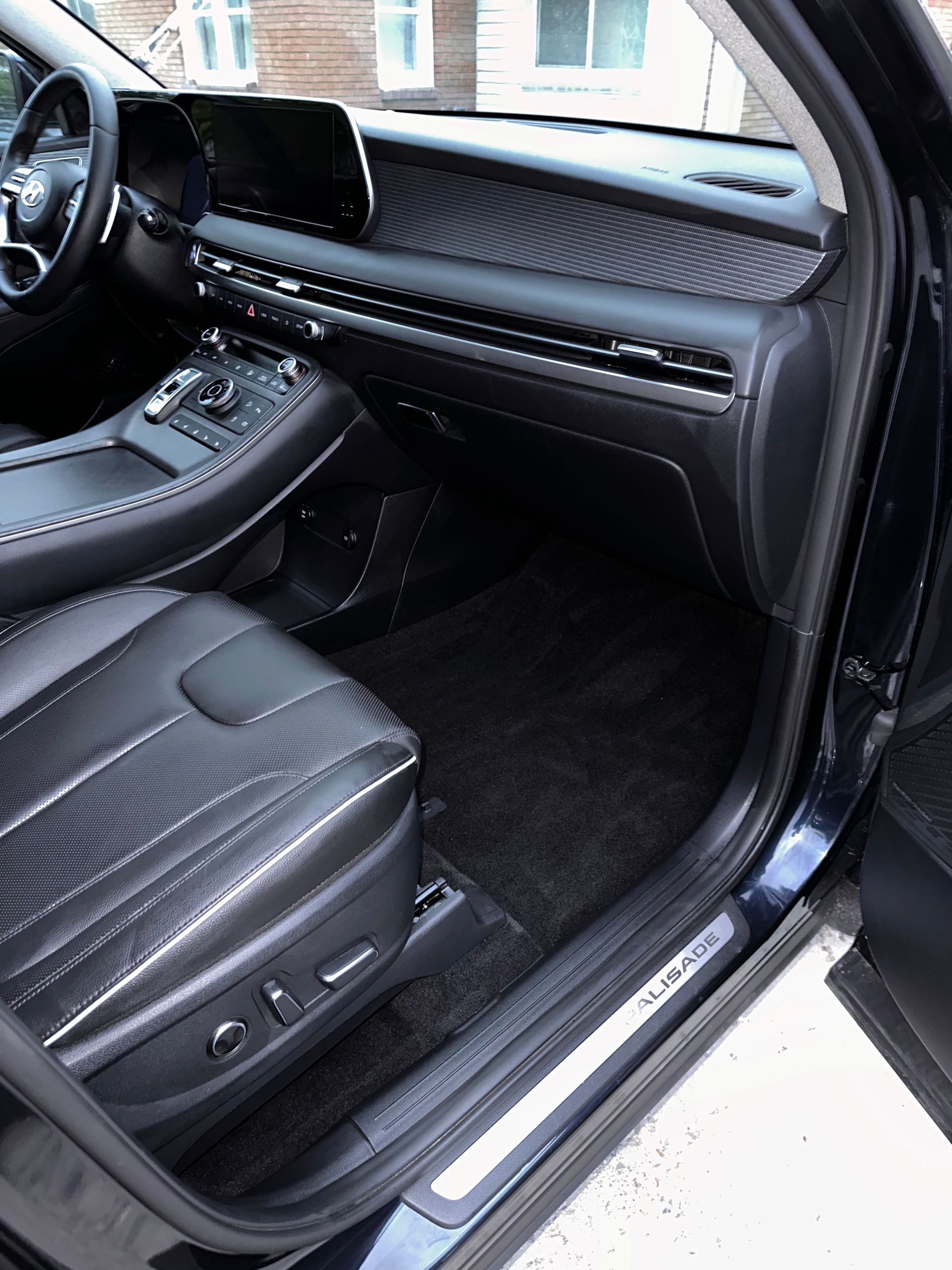 Black car interior with leather seats, dashboard, and door sill.