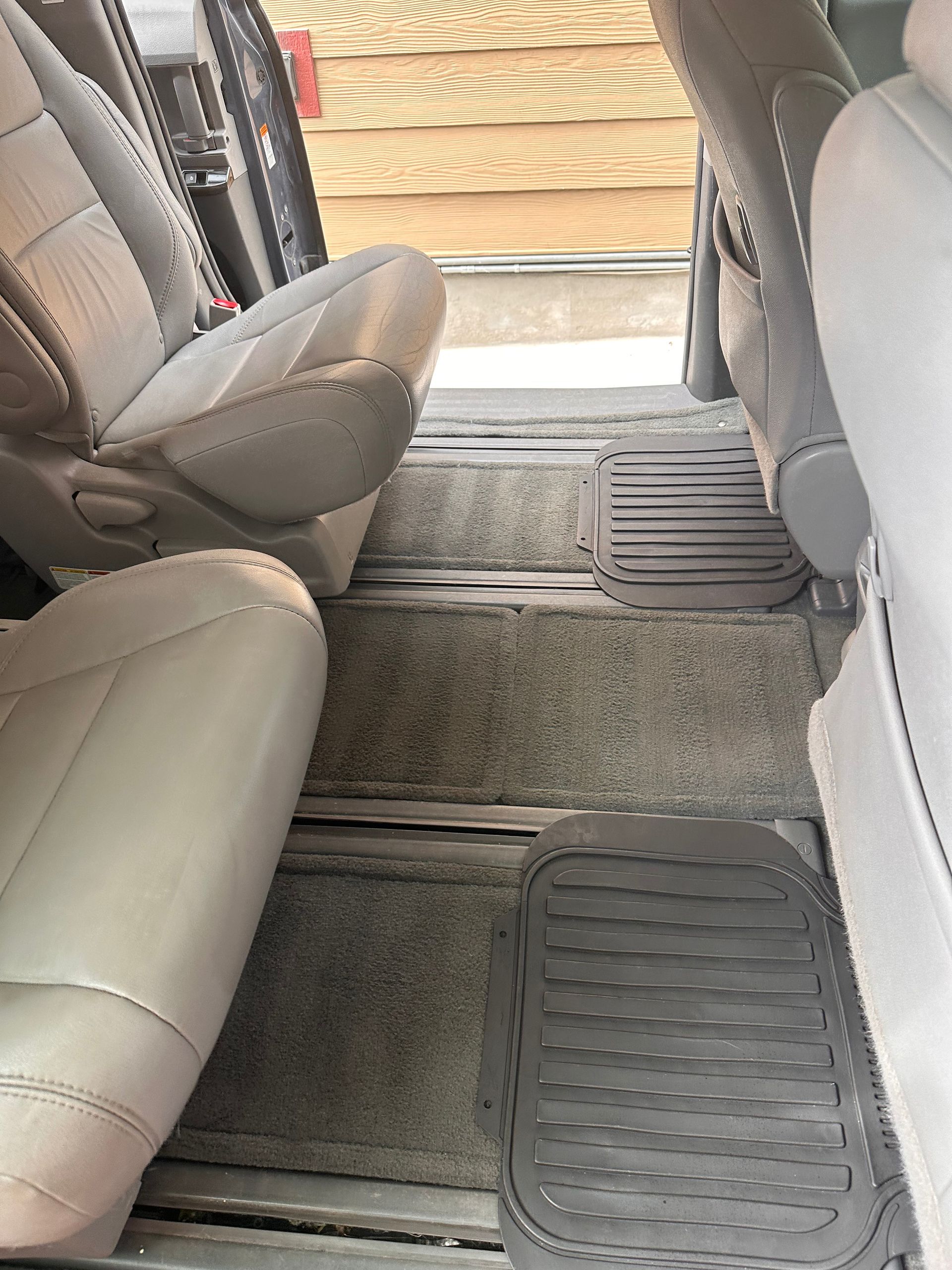 Van interior, showing grey seats, carpet, and a rubber floor mat.