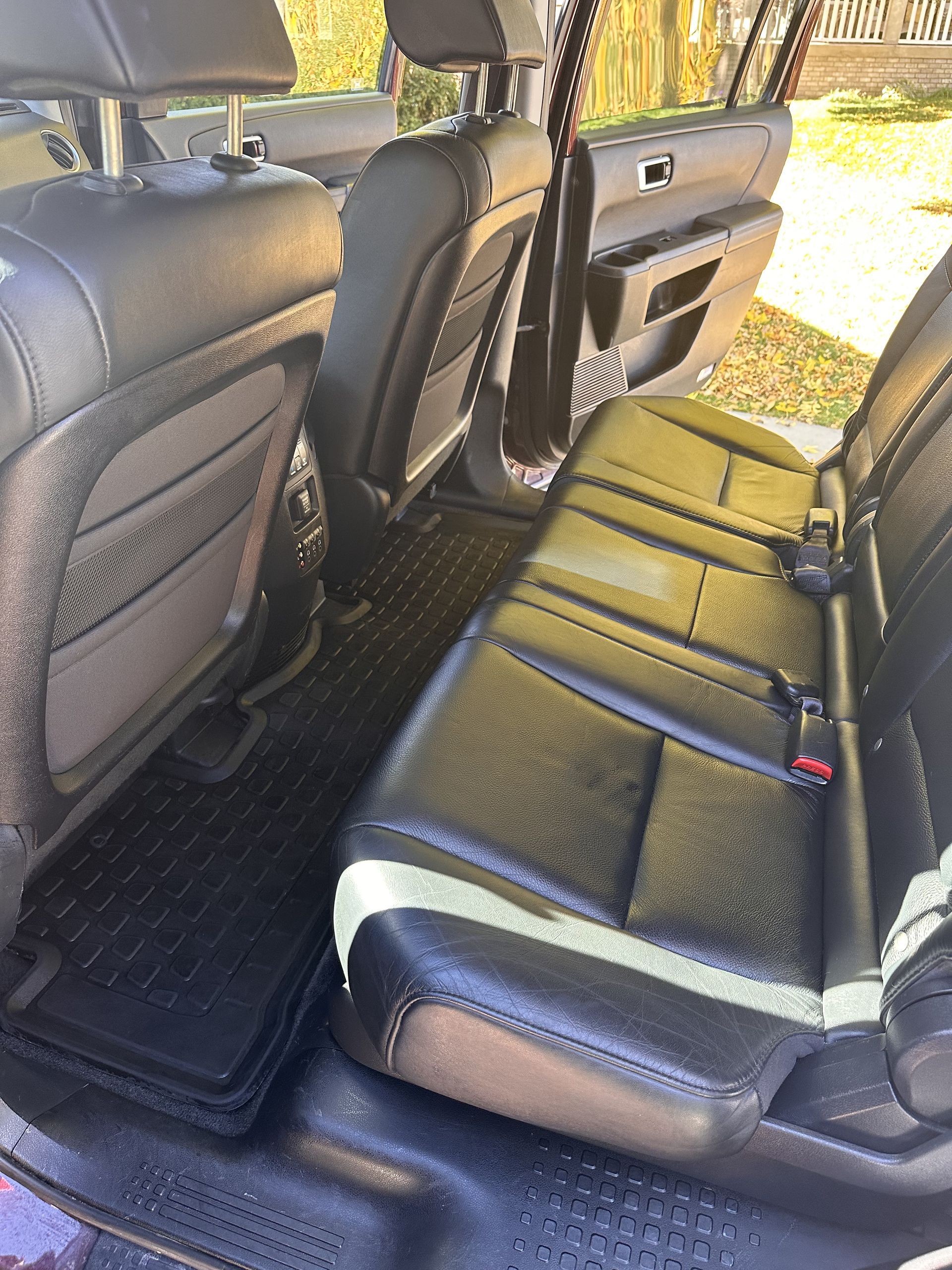 Black leather car seats and floor mats in the back of a vehicle.