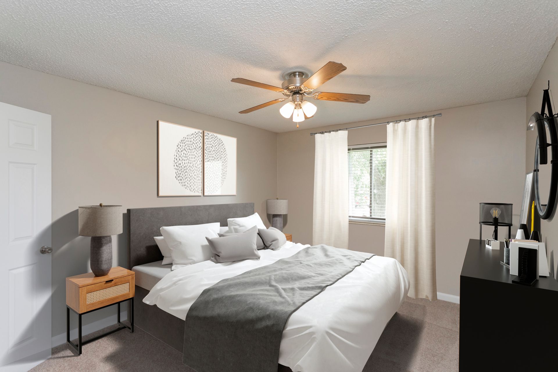A bright, neutral-toned bedroom with a grey bed, two wall art panels, a nightstand, and a ceiling fan.
