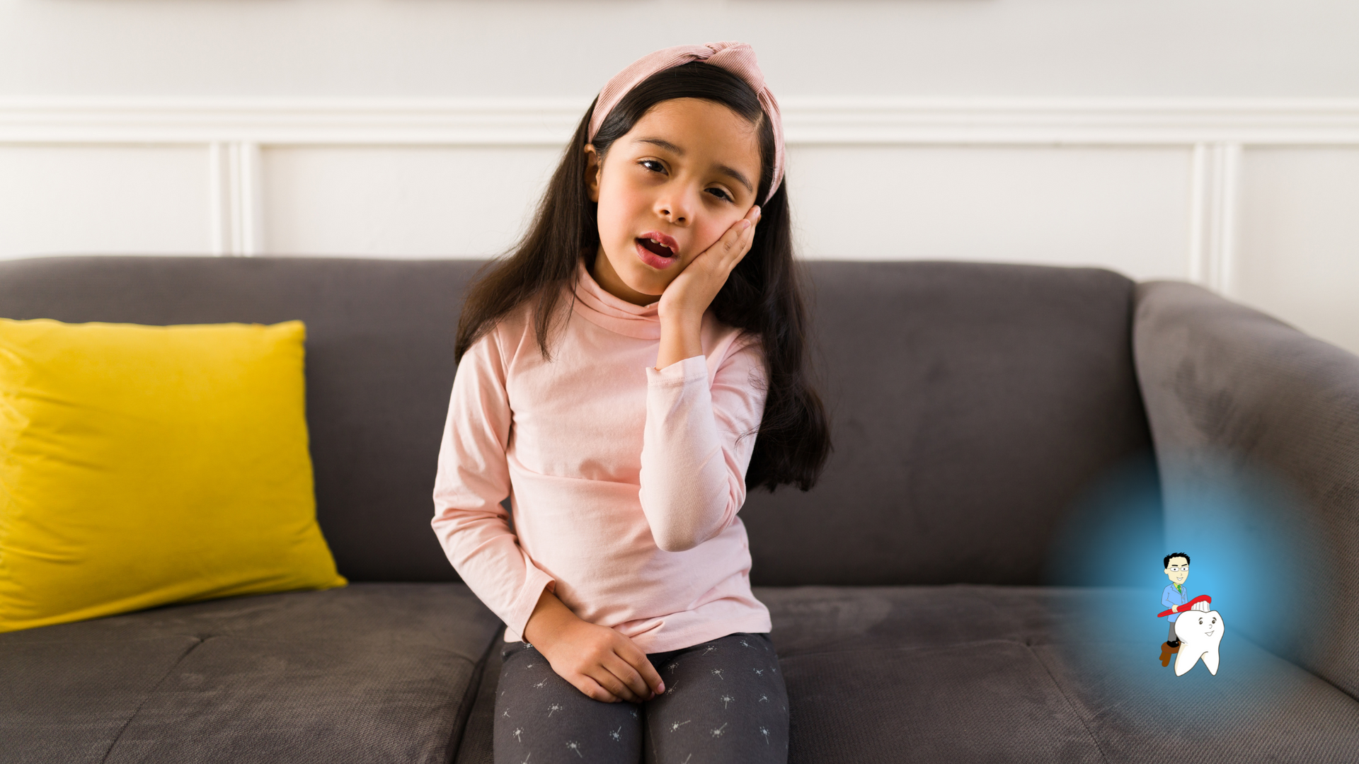 A little girl is sitting on a couch with a toothache.