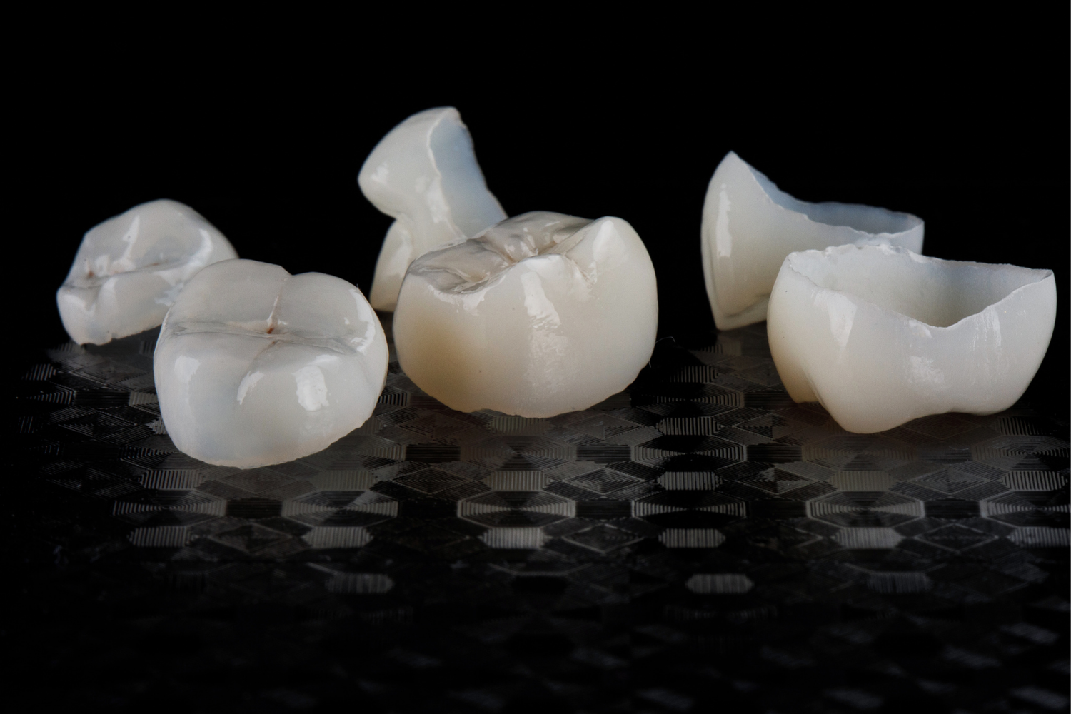 Dental tool applying gel to a white tooth beside pink gums