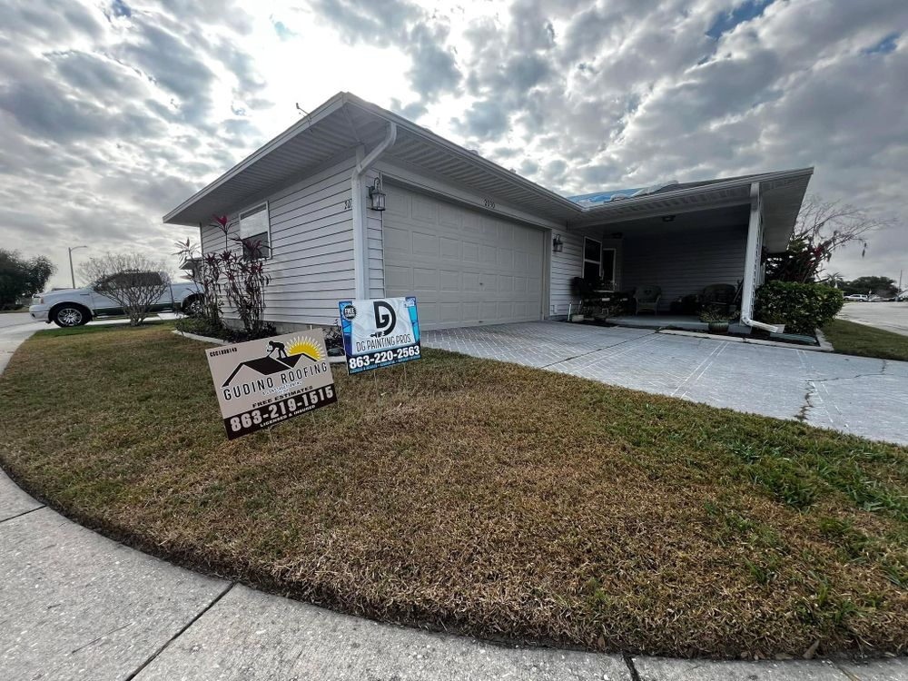 Single-story house with a covered carport, cloudy sky, and real estate signs on the front lawn