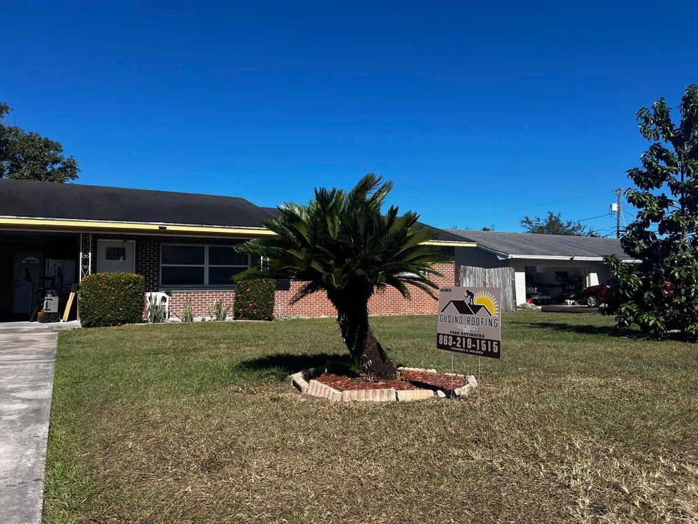 Single-story house with a palm tree and real estate sign on a sunny lawn