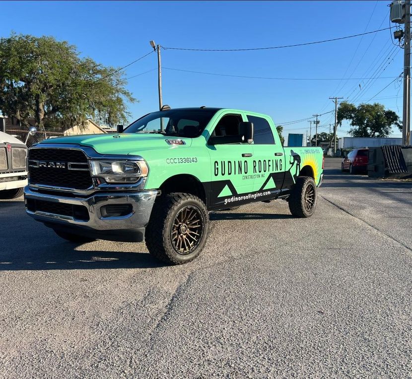 Neon green lifted pickup truck with black wheels parked on a gravel lot under a blue sky.