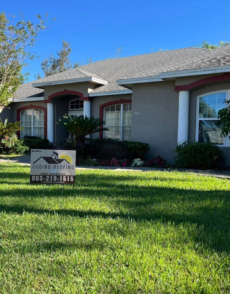 Single-story suburban house with manicured lawn and a real estate sign in front under a blue sky