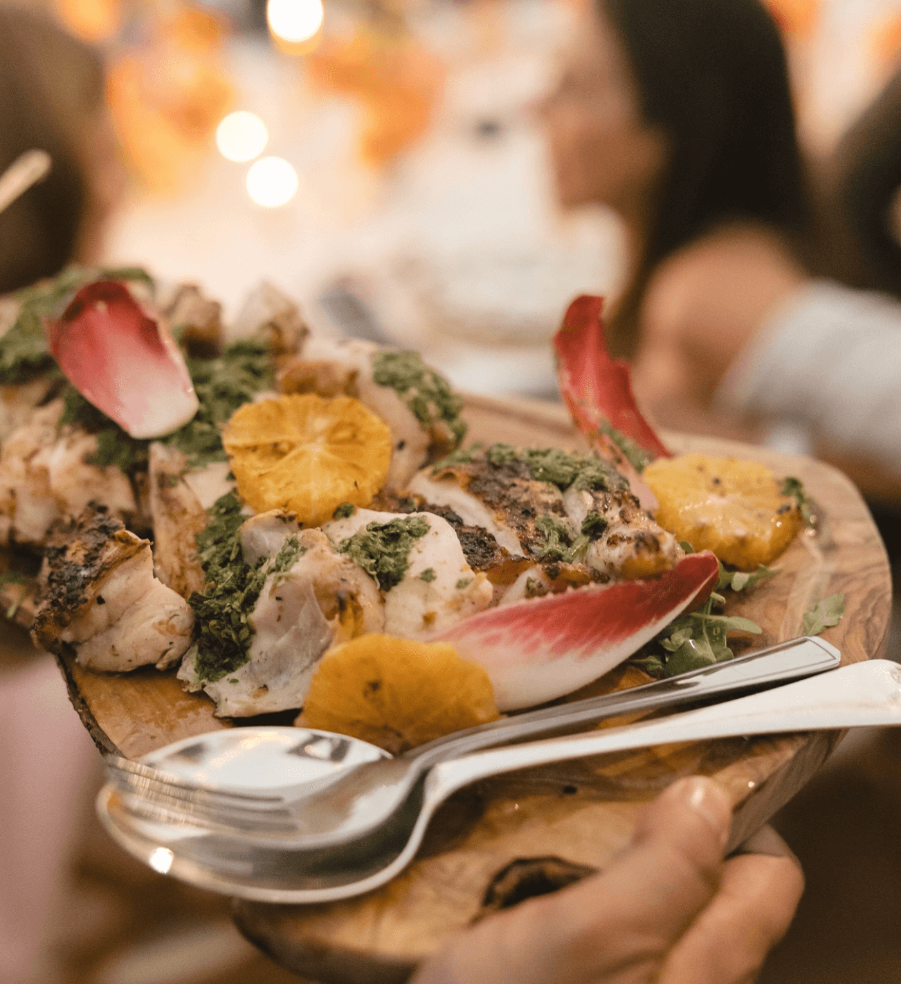 Chicken sharing plate with chicory, orange slices and a green herby sauce