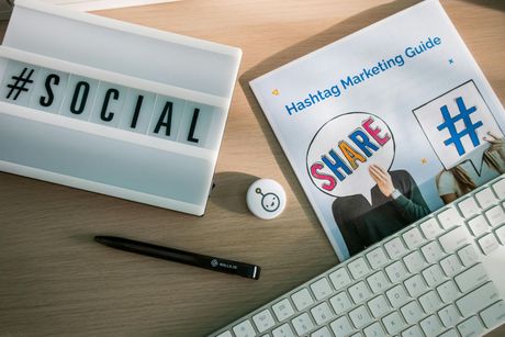 木桌上放著「#SOCIAL」標誌、社群媒體指南、鍵盤、筆和咖啡杯。